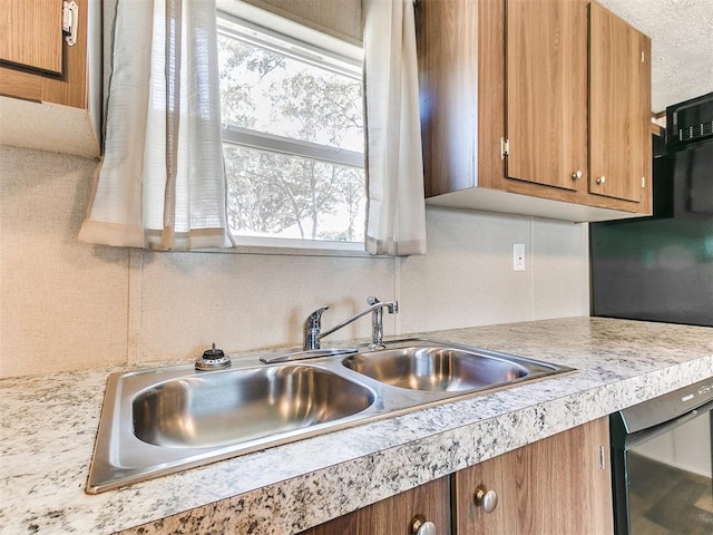 kitchen featuring brown cabinets, light countertops, a sink, and fridge