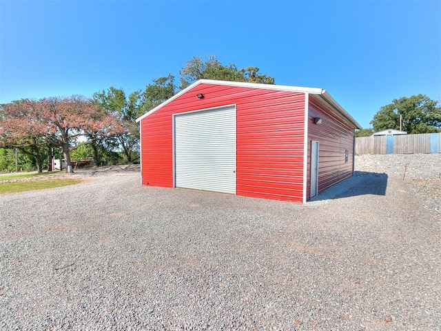 detached garage with gravel driveway and fence