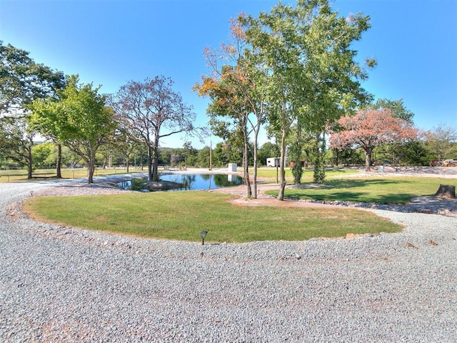 surrounding community with a water view and a yard