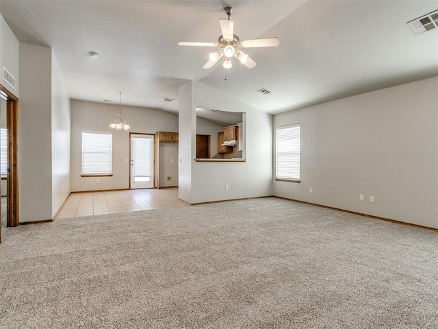 spare room with light carpet, a wealth of natural light, vaulted ceiling, and visible vents