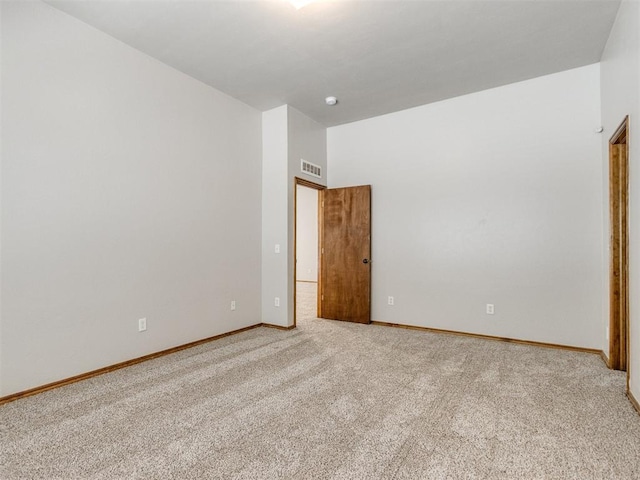 empty room with carpet floors, visible vents, and baseboards