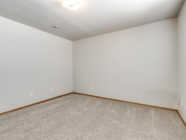 spare room with light carpet, visible vents, and baseboards