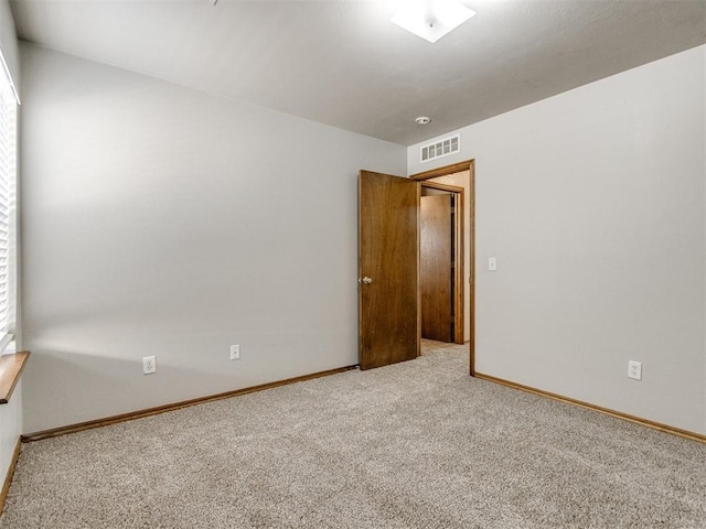 spare room featuring baseboards, visible vents, and carpet flooring