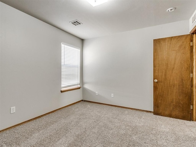 empty room featuring carpet floors, baseboards, and visible vents