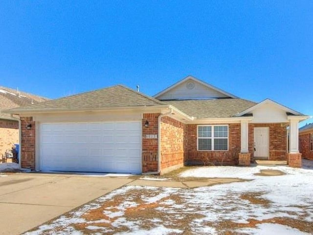 view of front of house featuring brick siding, an attached garage, driveway, and roof with shingles