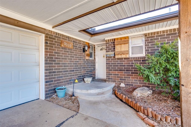 doorway to property with a garage and brick siding