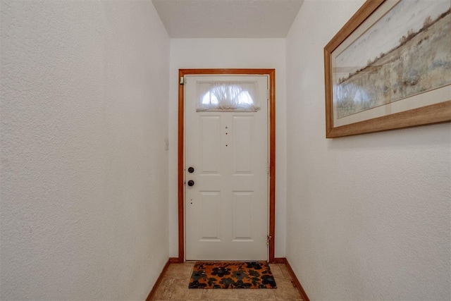 entryway with a textured wall and baseboards