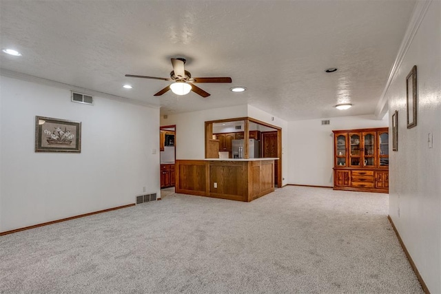 unfurnished living room with a textured ceiling, visible vents, and light colored carpet