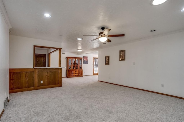 empty room featuring baseboards, light colored carpet, ceiling fan, ornamental molding, and a textured ceiling