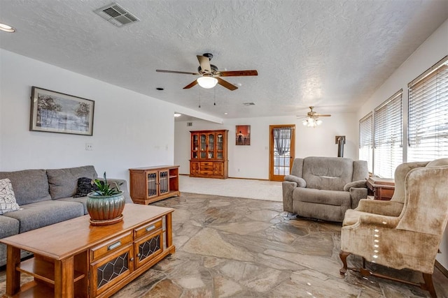 living area with a textured ceiling, visible vents, and a ceiling fan