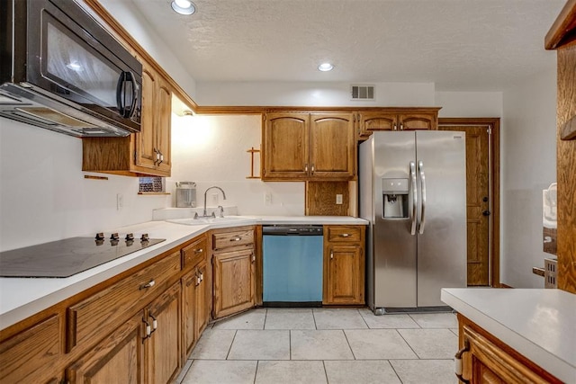 kitchen featuring black appliances, brown cabinetry, a sink, and light countertops