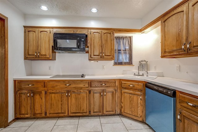 kitchen with black appliances, brown cabinetry, a sink, and light countertops