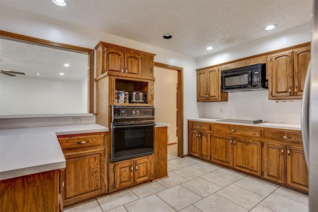 kitchen featuring light countertops, brown cabinets, a textured ceiling, and black appliances