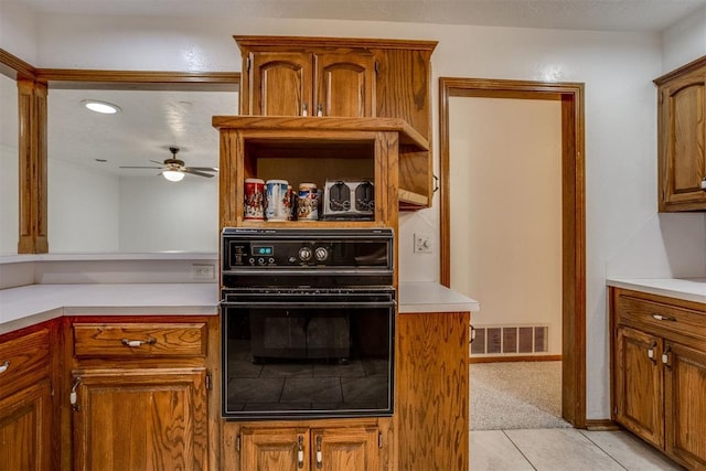 kitchen with light carpet, black oven, light countertops, and visible vents