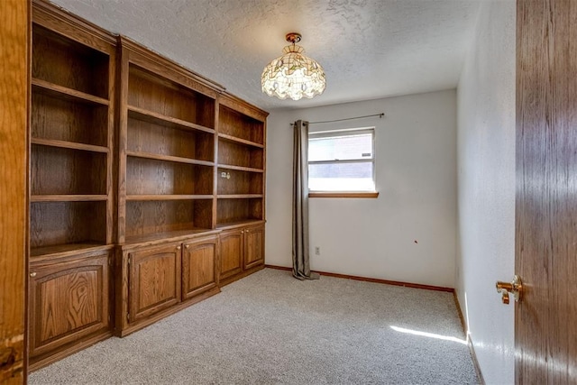 spare room featuring baseboards, a textured ceiling, and light colored carpet