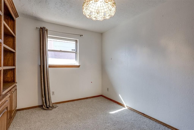 empty room featuring light carpet, baseboards, and a textured ceiling