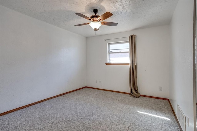 carpeted spare room with a ceiling fan, visible vents, a textured ceiling, and baseboards