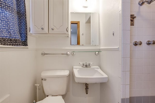 bathroom featuring wainscoting, a sink, and toilet