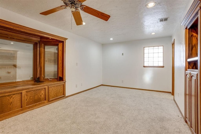 empty room featuring a textured ceiling, recessed lighting, light carpet, visible vents, and baseboards