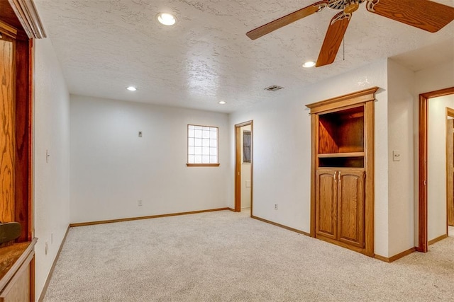 unfurnished room with baseboards, a textured ceiling, and light colored carpet