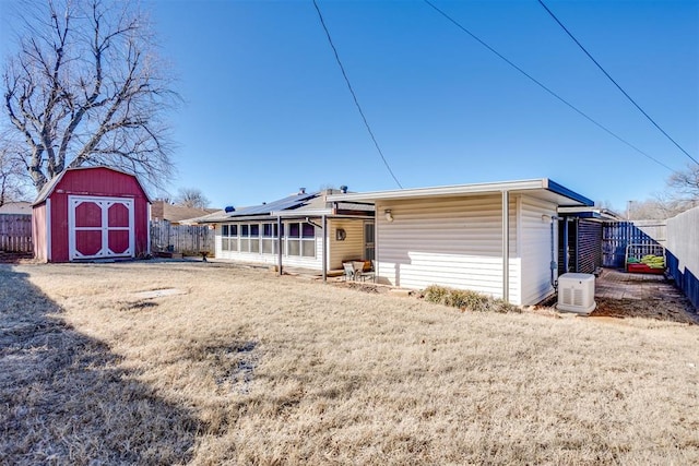 back of house featuring a storage shed, a lawn, an outbuilding, and a fenced backyard