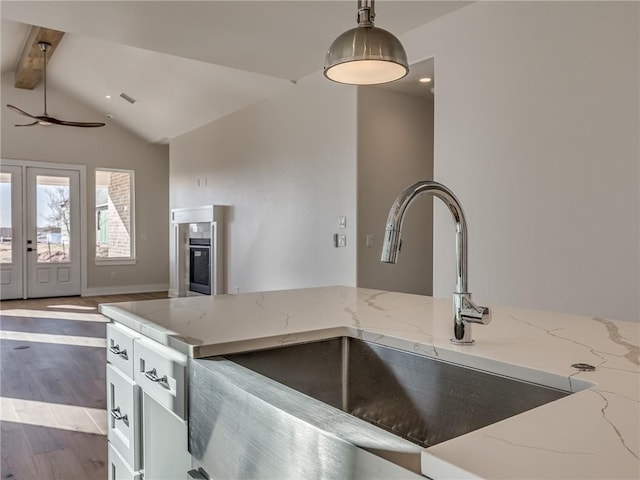 kitchen with decorative light fixtures, lofted ceiling with beams, a sink, wood finished floors, and a tile fireplace