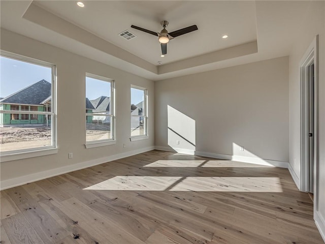 empty room featuring visible vents, a raised ceiling, and hardwood / wood-style floors