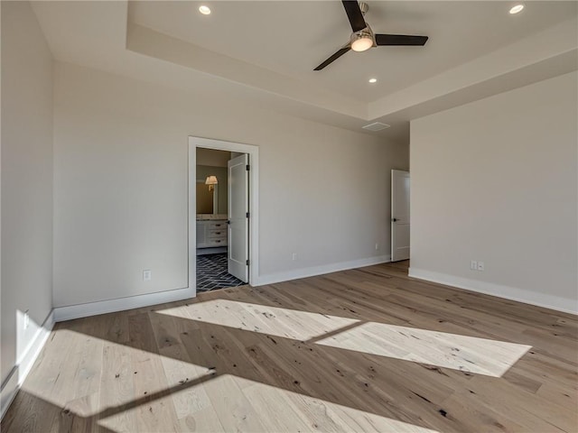 spare room with a tray ceiling, recessed lighting, hardwood / wood-style floors, and baseboards