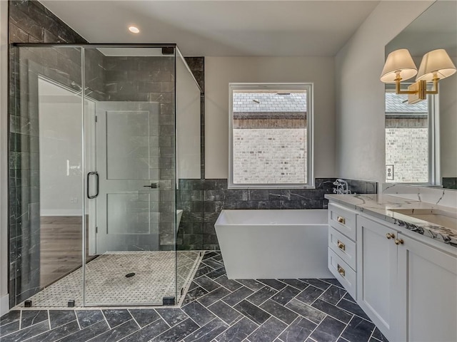 full bathroom featuring tile walls, a freestanding tub, vanity, and a shower stall