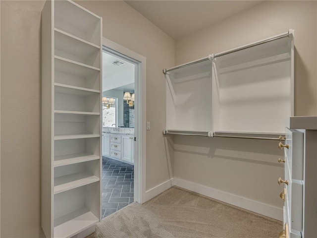 walk in closet with carpet floors, visible vents, and a sink