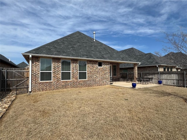 rear view of house featuring a patio area, a fenced backyard, a shingled roof, and brick siding