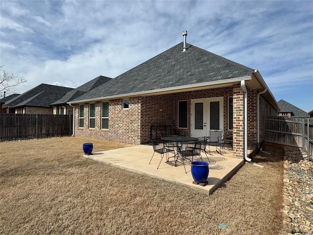 rear view of property featuring a patio area, a fenced backyard, a yard, and brick siding