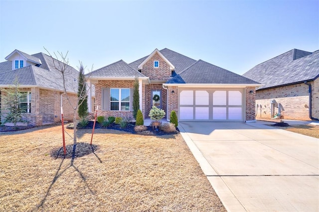 view of front of property with driveway, a front yard, a shingled roof, a garage, and brick siding