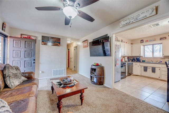 living room featuring light tile patterned floors, light carpet, visible vents, and a ceiling fan