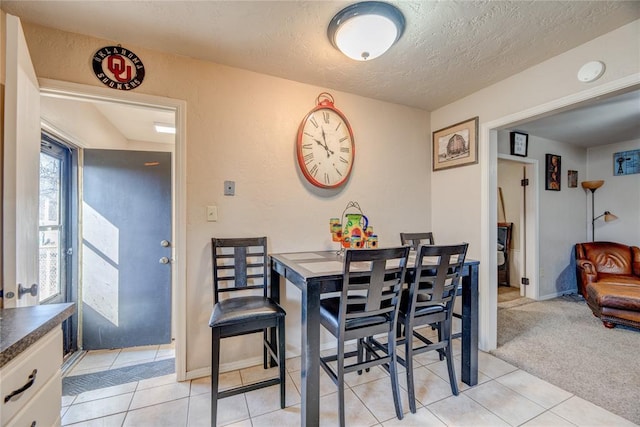 dining space featuring light tile patterned flooring, a textured ceiling, and light colored carpet