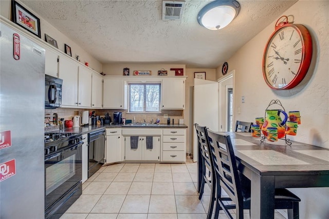 kitchen featuring black appliances, light tile patterned floors, white cabinetry, and decorative backsplash