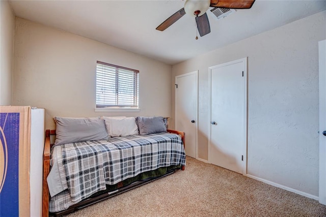 carpeted bedroom featuring a ceiling fan and visible vents