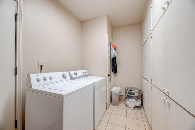 clothes washing area with light tile patterned flooring, cabinet space, and separate washer and dryer