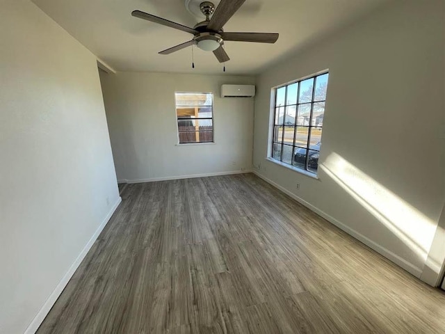 empty room with ceiling fan, baseboards, an AC wall unit, and wood finished floors