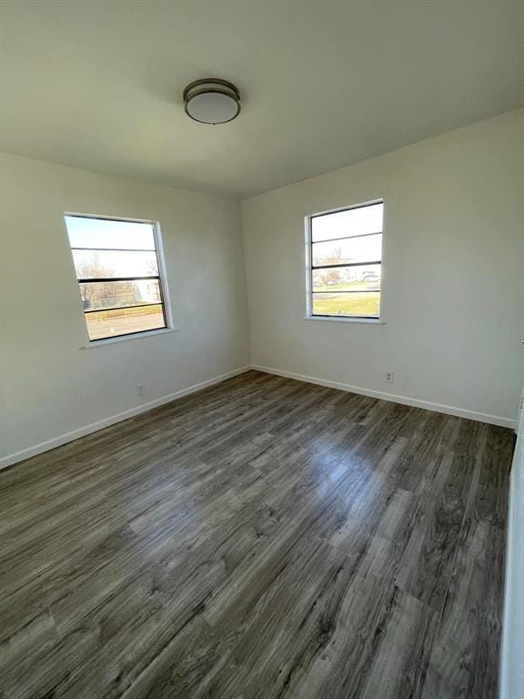 empty room with dark wood-type flooring and baseboards