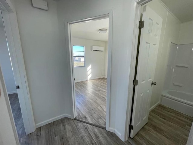 hall featuring baseboards, wood finished floors, and a wall mounted AC