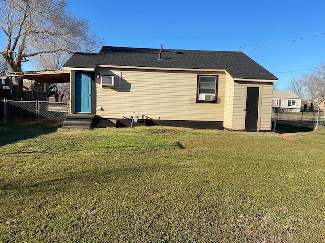 back of house featuring roof with shingles, a lawn, and fence