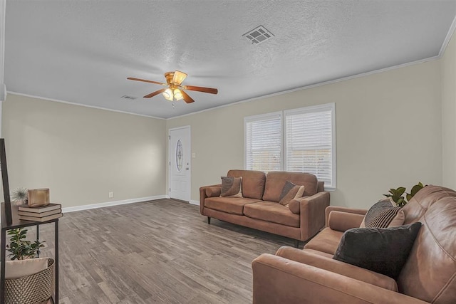 living room featuring baseboards, visible vents, wood finished floors, crown molding, and a textured ceiling