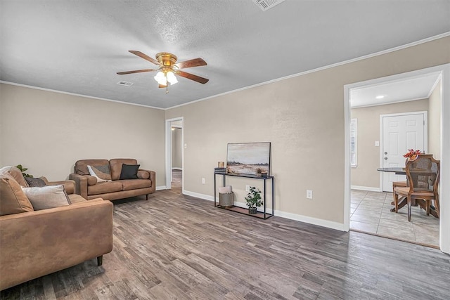 living room with baseboards, ceiling fan, ornamental molding, and wood finished floors