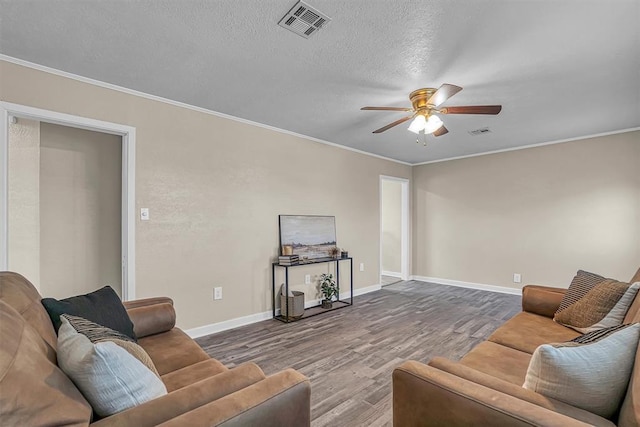 living area with ceiling fan, crown molding, visible vents, and wood finished floors