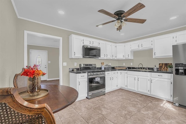 kitchen featuring dark countertops, appliances with stainless steel finishes, a sink, and ornamental molding