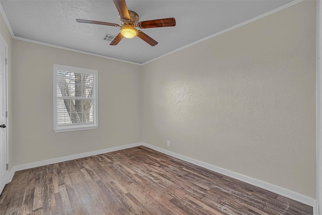 spare room featuring crown molding, visible vents, a textured ceiling, wood finished floors, and baseboards