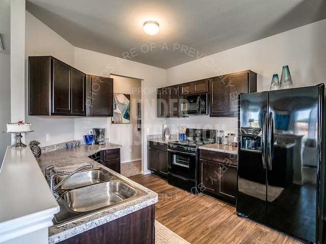 kitchen with a sink, dark brown cabinets, light countertops, dark wood-style floors, and black appliances