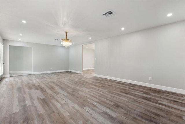 spare room featuring baseboards, wood finished floors, visible vents, and recessed lighting