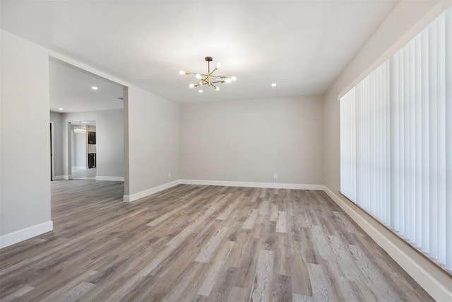 unfurnished room with light wood-style floors, recessed lighting, baseboards, and an inviting chandelier